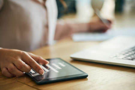 Hand, graph and technology while a woman zoom in on a tablet to check the growth and development of...