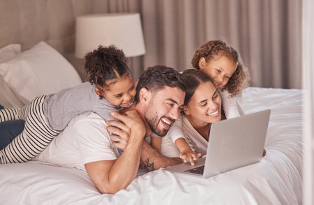 Happy family streaming movies on laptop in bedroom for online entertainment to relax during the...
