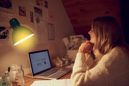Who needs sleep when youve got uncapped internet. a young woman using her laptop in her bedroom at night.の写真素材