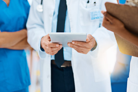 Become a patient online and get the same professional advice. a group of medical professionals discussing something on a digital tablet.の写真素材