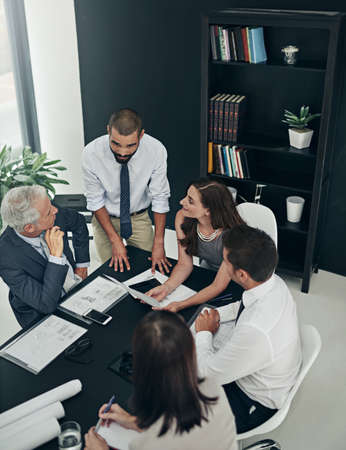Discussing the way forward. High angle shot of a group of businesspeople meeting in the boardroom.