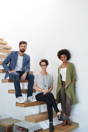 Were ready to put success in action. Portrait of three young creatives alongside a staircase in a modern office.の写真素材