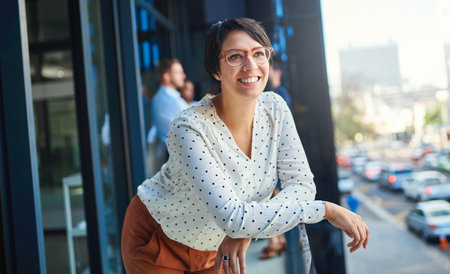 The future looks bright from where Im standing. a young businesswoman standing on a balcony with her...