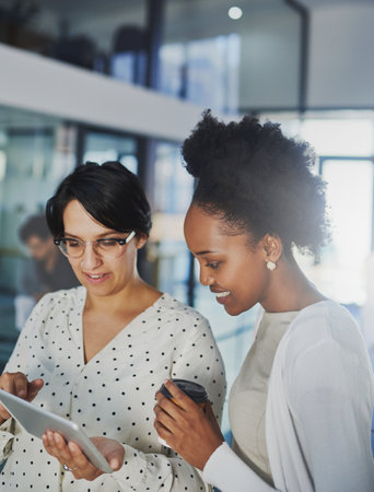 Oh wow, that looks really great. two businesswomen looking at a tablet in the office.の写真素材