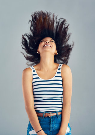 Carefree and cheery. a carefree young woman posing against a grey background.