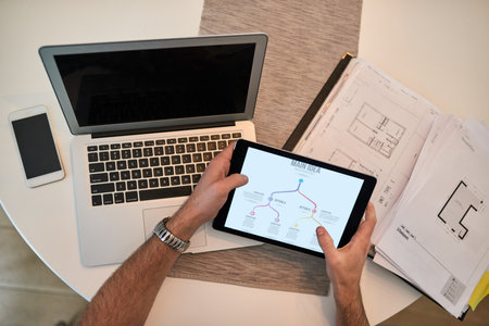 Working with big plans in mind. High angle shot of a man using wireless technology to work at home.