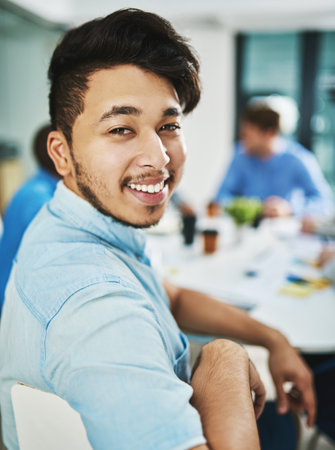 It feels good knowing that youre doing good. Portrait of a young designer sitting in the boardroom with his colleagues.の写真素材