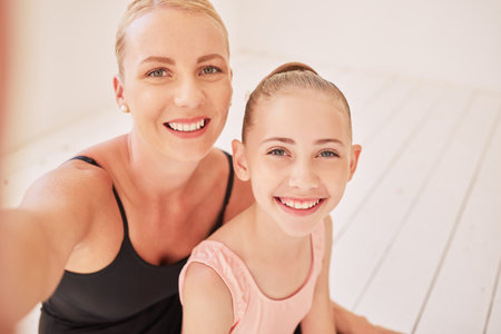 Family, dance and ballet with a mother and her young daughter taking a selfie in a dancing studio for the performing arts. Portrait of a child ballerina and her parent training for a recital or showの写真素材