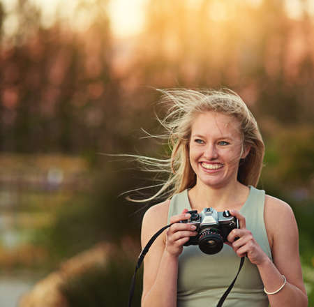 On the look out for some perfect shots. a young woman taking photos on her camera outside.の写真素材