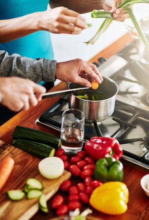 The better the ingredients, the better the meal. High angle shot of an unidentifiable couple cooking together in their kitchen at home.の写真素材