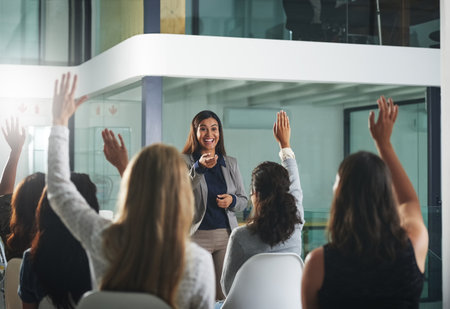 Taking some questions from the audience. a group of businesspeople raising their hands during a presentation.の写真素材