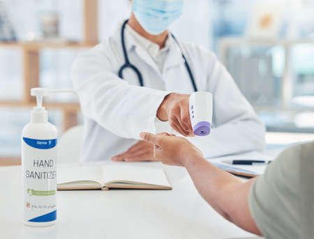 Covid, doctor and thermometer for a safety hygiene check with a patient during corona virus in...