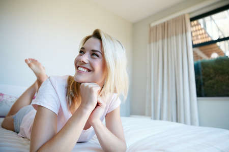 Allow your mind to wander. a young woman relaxing in her bedroom.の写真素材
