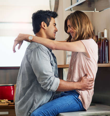 I love you. an affectionate young couple arm in arm in the kitchen.