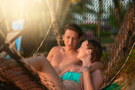 We should do this more often. a young couple relaxing on a hammock at the beach.の写真素材