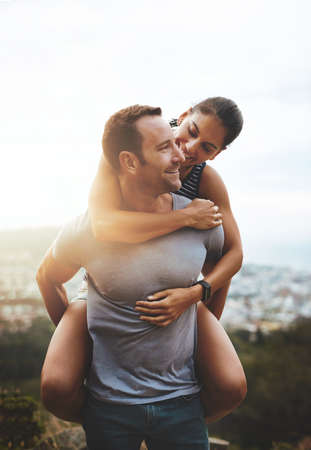 Where to next. a happy young couple enjoying a piggyback ride outdoors.の写真素材