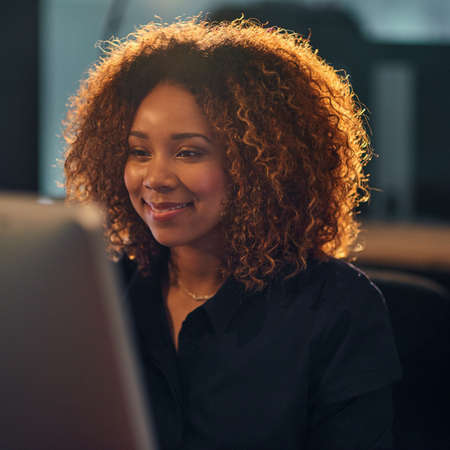 Hard work makes great work. a happy young businesswoman using a computer during a late night at...