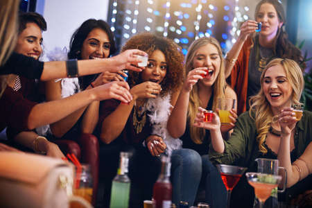 Three, two, one - down. a group of friends having shots together at a party.の写真素材