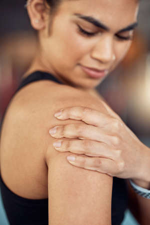 Gym, fitness and sad woman with shoulder pain due to an exercise, workout or training routine in a wellness center. Inflammation and muscle strain for female athlete in a gym with a painful armの写真素材