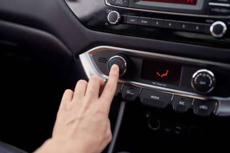 Cool down or warm up. Closeup shot of a driver adjusting the air conditioning of a motor vehicle.