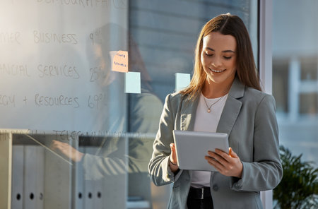 Corporate woman on tablet typing, smile and reading business leadership, motivation and success news. Happy young manager or girl boss at company working on online digital or internet management appの写真素材