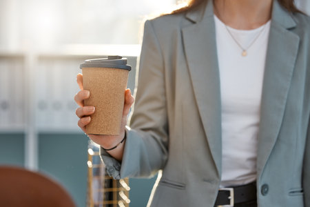 Coffee, business hand and work break for walking pedestrian woman on lunch, breakfast or tea stop in city, town or downtown. Zoom on takeaway cup for motivation routine or morning public work commuteの写真素材