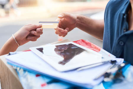 Just another simple option to pay for your delivery. a customer using a credit card to pay for a delivery made by a courier.の写真素材