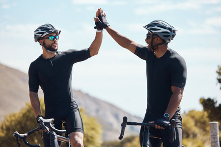 High five, winner and cycling team of cyclists having fun riding together outdoors in nature. Happy, excited and fit male bicycle riders on a break after exercising and training in the environmentの写真素材