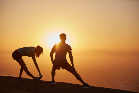 Warming up those muscles. a silhouetted couple out for a run at sunrise.の写真素材