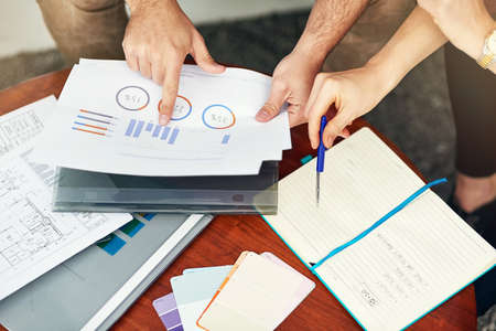 Its important to analyse every detail. High angle shot of people looking through some paperwork in...