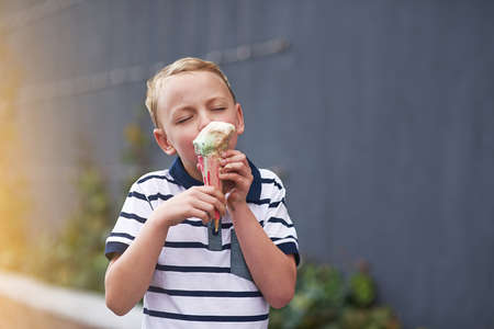 This ice cream is really good. a young boy enjoying an ice cream cone.