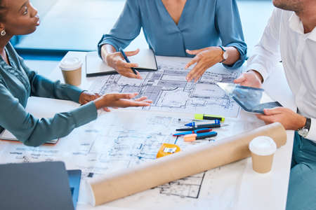 Blueprints, architects and building engineers talking, meeting and planning renovation, remodeling...