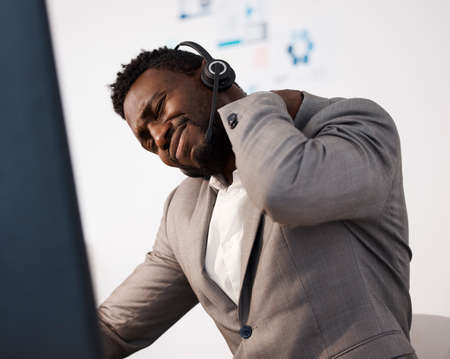 Stressed, pain and tired call center agent with a shoulder injury feeling unhappy and overworked in...