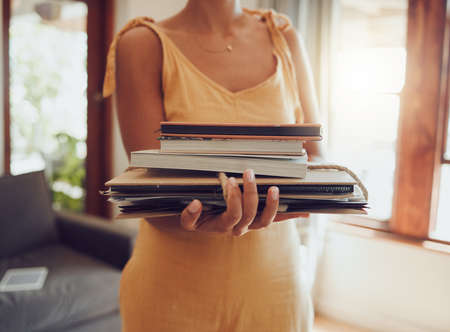 Recycle, books and notebook with woman cleaning or donating paper material in living room at home. Sustainability and eco cardboard waste management, for green living and clean future donationの写真素材