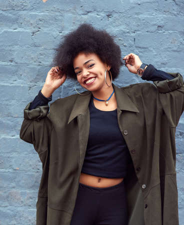 Feeling good today. Portrait of a happy young woman standing against a brick wall.の写真素材