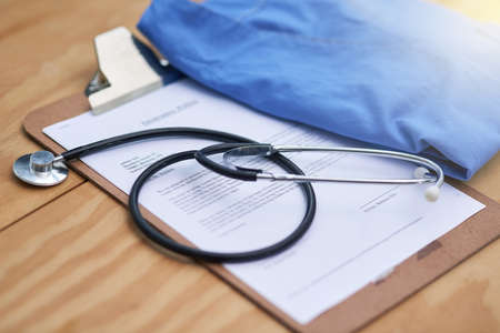 Diagnostic essentials. Closeup shot of a stethoscope lying on a doctors clipboard with a folded hospital gown.の写真素材