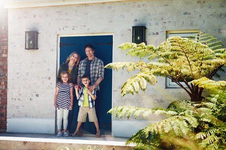 Welcome to our happy home. Portrait of a happy family standing outside their home.の写真素材