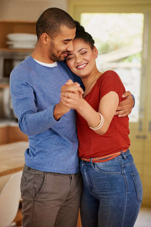 She loved him for the way he loved her. a happy young couple dancing together at home.