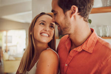 Couple, smiling and in love having a lovely romantic moment in the kitchen at home. Man and woman...