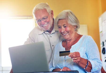 Time to spoil ourselves with a little help from technology. a senior couple using a laptop and...