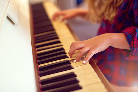 Sharpening up her musical skills. Closeup shot of a young girl playing the piano.の写真素材