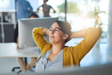 Driven by her dreams of success. a young businesswoman relaxing at her desk in a modern office.