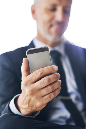 Staying connected, doing more. Closeup shot of a corporate businessman using a cellphone in an office.の写真素材