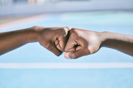 Closeup of hands, fist bump and the teamwork of two athletic, sporty, and active male athletes. Team of black people, friends or teammates working together showing respect, collaboration and supportの写真素材