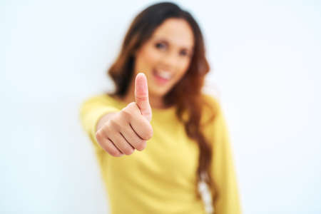 Thumbs up to that. Studio portrait of a gorgeous young woman posing against a light background.の写真素材