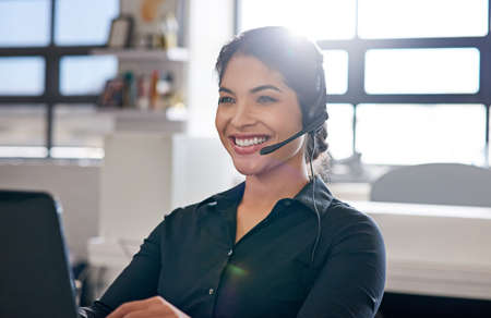 Happy agents make for happy clients. a call centre agent sitting at her desk in a modern office.