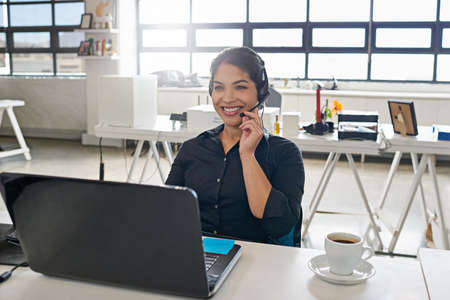 I have the solution to your problem. a call centre agent sitting at her desk in a modern office.の写真素材