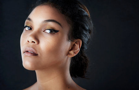 Keep your head up high, beautiful. a beautiful woman posing against a black background.の写真素材