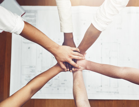 We always share the load. unrecognizable businesspeople joining their hands together in unity.
