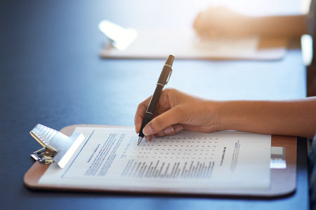 Completing the survey. an unrecognizable businesswoman filling in a questionnaire.の写真素材